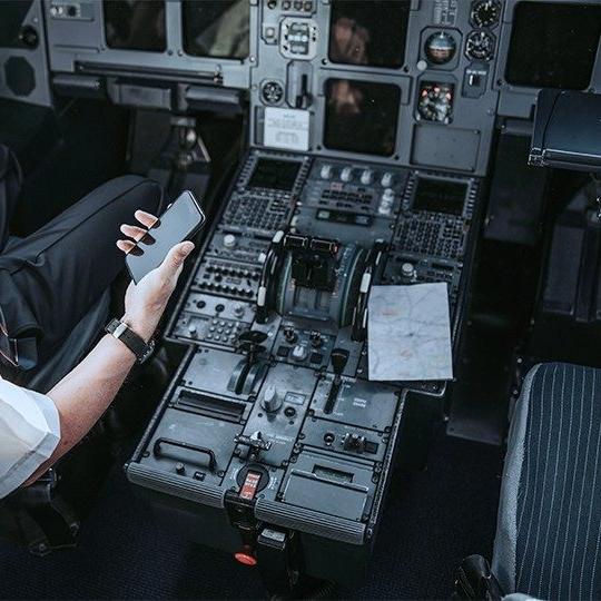 驾驶舱的特写和飞行员在智能手机上查看航空公司文件管理软件的左臂