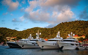Four charter yachts sitting in a bay next to a luscious mountain