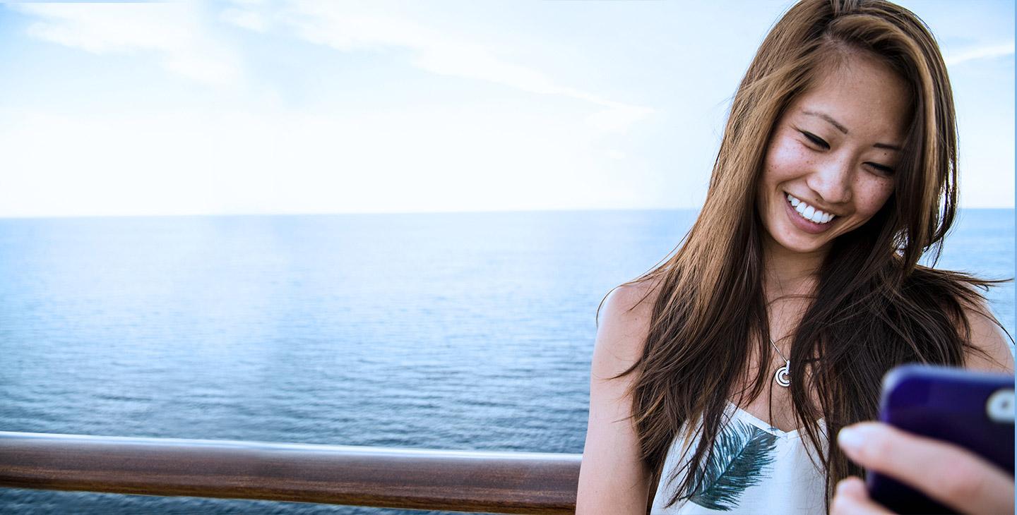 Woman on the deck of a boat at sea, video chatting with high speed internet at sea